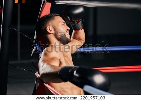 Tired boxer, fitness and sports competition in boxing ring, relax during mma fight and breathing after wellness exercise training at gym. Frustrated Muay Thai athlete without energy for workout