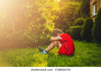 Tired boy after sport. A boy dressed in sports attire sits on the grass tired after playing football. - Powered by Shutterstock