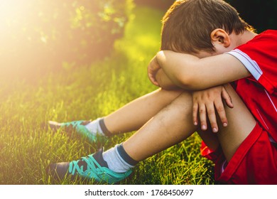 Tired boy after sport. A boy dressed in sports attire sits on the grass tired after playing football. - Powered by Shutterstock