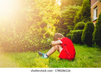 Tired boy after sport. A boy dressed in sports attire sits on the grass tired after playing football. - Powered by Shutterstock