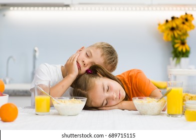 Tired boy and girl fell asleep in the morning at breakfast, not enough sleep - Powered by Shutterstock