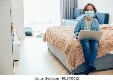 Tired Boy In A Medical Mask Sitting On The Edge Of His Bed With A Laptop On The Laps. Website Banner