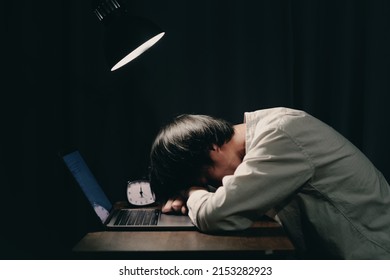 Tired Boy Sleeping At The Study Table. Laptop And Lights Left On Without Turning Off