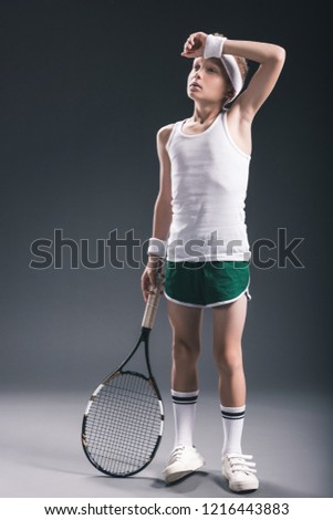 tired boy in sportswear with tennis racket on dark background