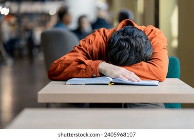 tired boy student sleeping in front of book in the library after preparing for university exams - Powered by Shutterstock