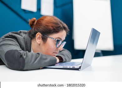 Tired business woman laid her head down on desk and looks at the laptop monitor. Female employee is tired at work in the office. - Shutterstock ID 1802015320