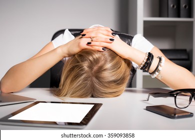Tired business woman resting her head on desk 