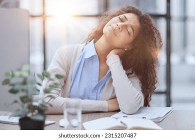 Tired business woman sitting at office desk and working - Shutterstock ID 2315207487