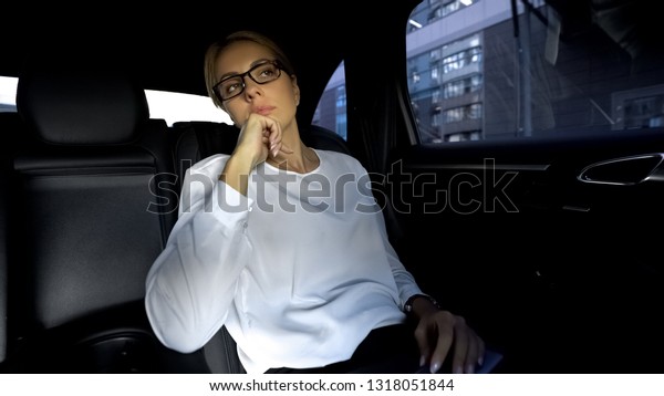 Tired businesslady sitting on backseat of car,\
going to meeting with\
partners