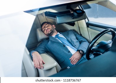 Tired Businessman In Eyeglasses Sleeping In Car