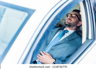 Tired Businessman In Eyeglasses Sleeping In Car