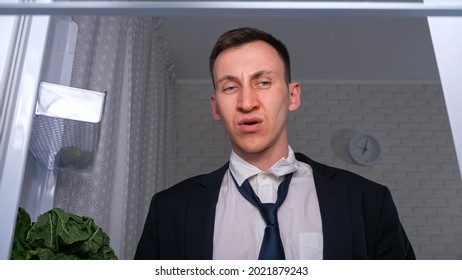 Tired Businessman In Office Suit Opens Fridge Door To Take Bottle Of Cold Beer From Shelf In Dark Kitchen Close View From Inside Refrigerator