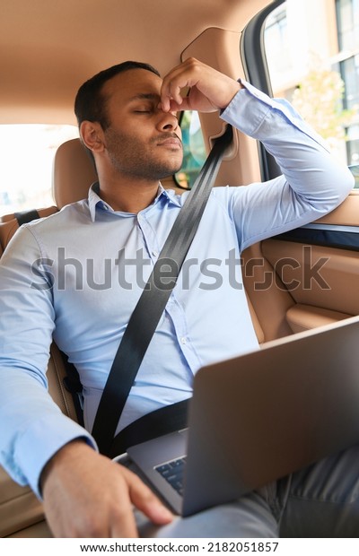 Tired businessman\
riding in backseat of car