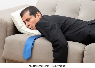 Tired businessman sleeping lying on a sofa in the living room at home after work