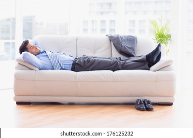 Tired businessman sleeping on a sofa in the office - Powered by Shutterstock