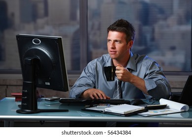 Tired Businessman Working Late Doing Overtime In Office At Night Drinking Coffee To Go On.