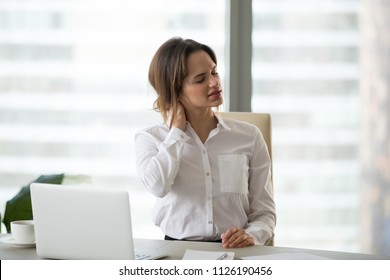 Tired businesswoman feels fatigue massaging tensed muscles of stiff neck trying to relieve pain after sedentary computer work in incorrect posture or uncomfortable office chair, fibromyalgia concept - Shutterstock ID 1126190456