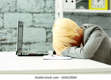 Tired businesswoman sleeping on her workplace in office