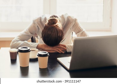 Tired businesswoman sleeping on table in office. Young overworked exhausted girl working from home. Woman using laptop. Entrepreneur, business, freelance work, student, stress, work from home concept