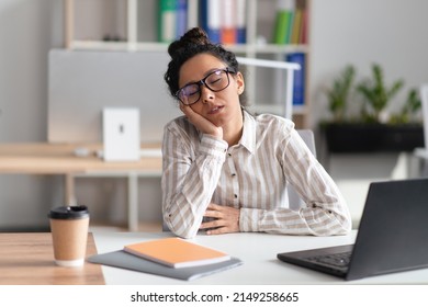 Tired businesswoman sleeping at workplace while working at laptop computer in modern office interior. Insomnia and fatigue problem, boring job concept