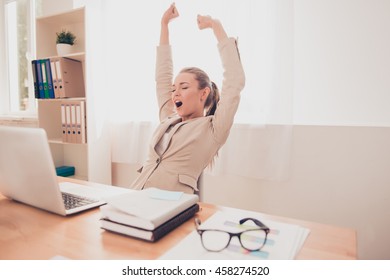 Tired businesswoman stretching and yawning after working day