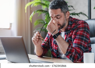 Tired caucasian man suffer from headache bad vision sight problem sitting at home table using laptop - Powered by Shutterstock