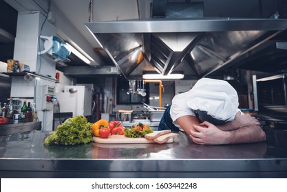Tired chef worker fall asleep during working hours in the kitchen of a restaurant