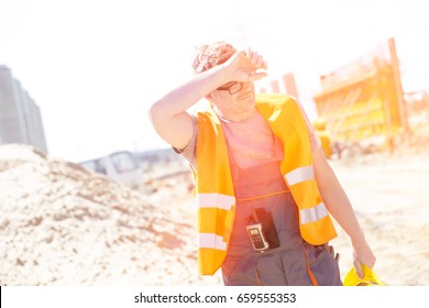 Tired Construction Worker Wiping Forehead At Site