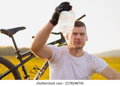 Tired cyclist refreshes splashing water on his face from a bottle after riding bike during the hot sunny days. Young sports man resting after exercise or workout outdoors. Active healthy lifestyle. - Powered by Shutterstock