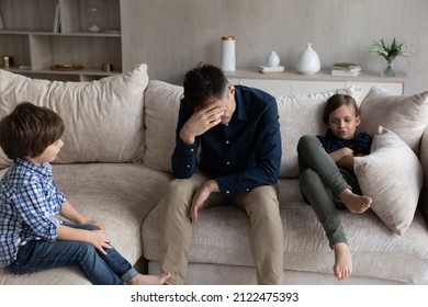 Tired dad and bored sibling kids going through conflict, resting on couch. Frustrated young single father and stubborn children ignoring each other, arguing. Parenthood, fatherhood, behavior problems