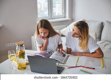 Tired Daughter Concentrating On A Dull Course Book Topic With A Parent Looking Over Her Shoulder