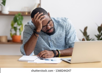 Tired depressed bored african businessman frustrated by business failure bankruptcy looking at laptop feel exhausted having headache, upset stressed black office worker worried about problem at work - Shutterstock ID 1368244247