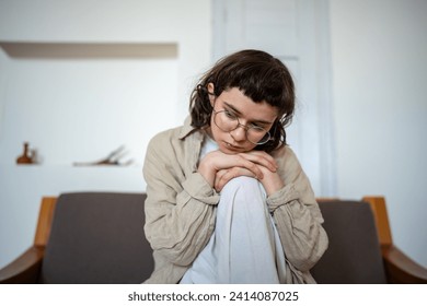 Tired depressed desperate tired teen girl sadly sitting on couch at home. Upset teenager boring. Nervous schoolgirl feels frustration hiding from society in loneliness solitude. Psychological problem