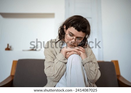 Tired depressed desperate tired teen girl sadly sitting on couch at home. Upset teenager boring. Nervous schoolgirl feels frustration hiding from society in loneliness solitude. Psychological problem