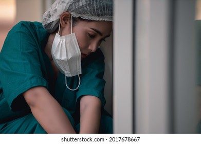 Tired Depressed Female Asian Scrub Nurse Wears Face Mask Blue Uniform Sits On Hospital Floor,Young Woman Doctor Stressed From Hard Work