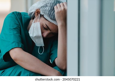 Tired depressed female asian scrub nurse wears face mask blue uniform sits on hospital floor,Young woman doctor stressed from hard work - Powered by Shutterstock