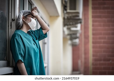 Tired Depressed Female Asian Scrub Nurse Wears Face Mask Blue Uniform Sits On Hospital Floor,Young Woman Doctor Stressed From Hard Work