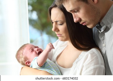 Tired Desperate Parents Holding Their Baby Crying Desperately At Home