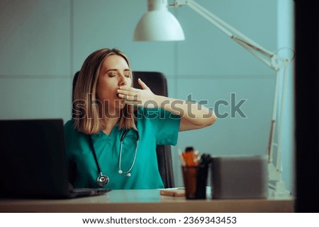 
Tired Doctor Yawning Covering her Mouth Sitting at the Desk. Sleepy medical practitioner working in a night shift 
