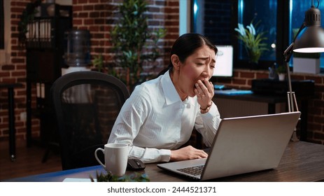 Tired employee asleep on computer desk chair suddenly waking up, struggling to finish writing emails. Drowsy businesswoman working overnight, typing on laptop, trying to stay awake, camera A - Powered by Shutterstock