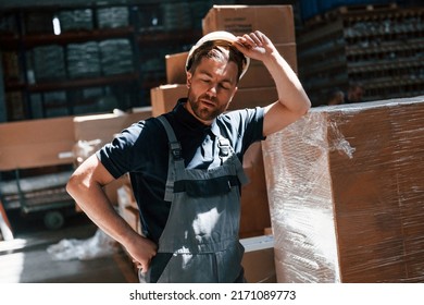 Tired Employee In Uniform Is Working In The Dark Storage.