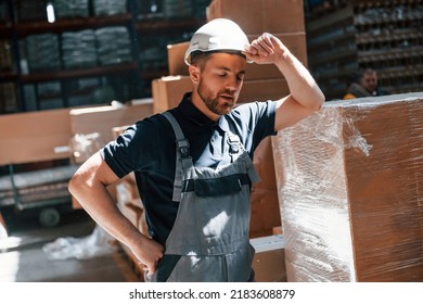 Tired Employee In Uniform Is Working In The Dark Storage.