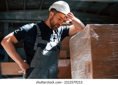 Tired Employee In Uniform Is Working In The Dark Storage.