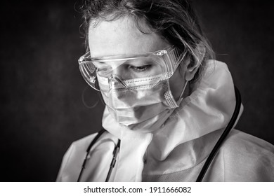 Tired Exhausted Doctor In Personal Protective Equipment (PPE), Nurse Wearing Goggles And Face Mask, Portrait Of Worker In Medical Professional Suit Due To COVID-19 Corona Virus. Health Care Concept.