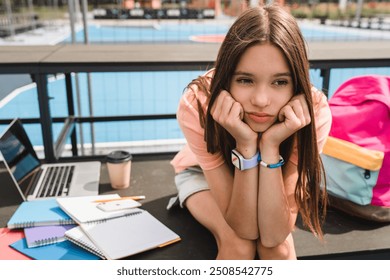 Tired exhausted high school girl teenager pupil college student in casual clothes with bag using laptop doing home work task sitting alone in sport yard basketball court copy space. Education concept - Powered by Shutterstock