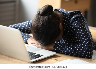 Tired exhausted Indian woman falling asleep at desk close up, sitting at table with laptop, lack of sleep and insomnia concept, overworked unmotivated girl lying on table, feeling boredom