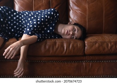 Too Tired. Exhausted Millennial Hispanic Woman Lying On Big Leather Sofa Taking Break Spending All Forces On General Cleaning Of House. Fatigue Powerless Young Latin Lady Rest From Hard Work On Couch