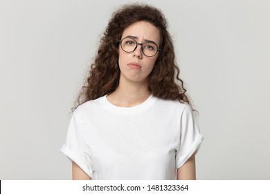 Tired exhausted millennial woman in eyewear feeling bored, lack of motivation, apathy, isolated on grey white studio background head shot close up portrait. Sad unhappy girl with frowning expression.