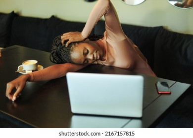 Tired, Exhausted, Stressed Afro American Businesswoman Or Student, Lying On Table At Laptop In Cafe With Cup Of Coffee. Meet Deadline, Need Sleep, Rest. Remote Online Freelance Job, Burn Out At Work