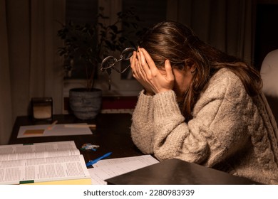 Tired exhausted student trying to study in the night at home scratching her eyes with her hands and holding her glasses. Young woman falling asleep while studing at night in her room - Powered by Shutterstock